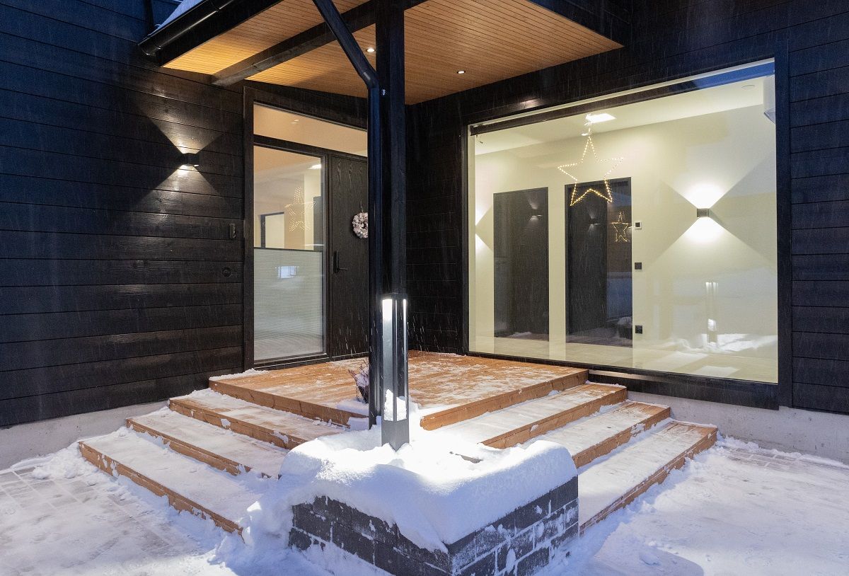 The entrance to the house is beautifully lit. In addition to the black exterior wall lights and the black pillar light in the planting pool, the entrance is illuminated by black 9W spotlights on the ceiling